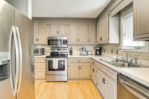 A modern kitchen with stainless steel appliances, beige cabinetry, and a large window providing natural light. - 1 Mi to Broadway at the Beach: Home w/ Large Yard! (Myrtle Beach)