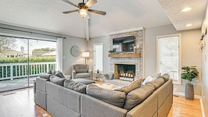 A spacious living room with a sectional sofa, a fireplace, and a ceiling fan. - 1 Mi to Broadway at the Beach: Home w/ Large Yard! (Myrtle Beach)