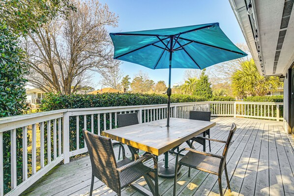 A wooden deck with a table and chairs, a blue umbrella, and a white railing. - 1 Mi to Broadway at the Beach: Home w/ Large Yard! (Myrtle Beach)