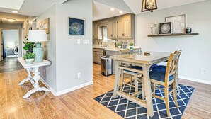 A modern kitchen with wooden cabinets, a dining table with chairs, and a hanging light fixture. - 1 Mi to Broadway at the Beach: Home w/ Large Yard! (Myrtle Beach)