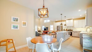 Una cocina amplia con armarios blancos, una mesa de comedor de madera y una lámpara colgante.