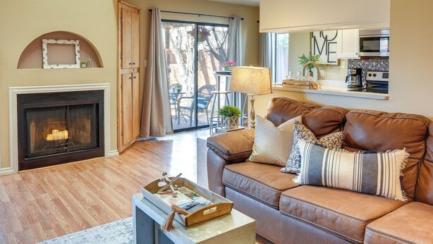 Una sala de estar acogedora con chimenea, un sofá de cuero marrón y un comedor con mesa y sillas.