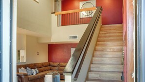 Una escalera con escalones de madera y barandilla de metal que lleva a una pared roja.