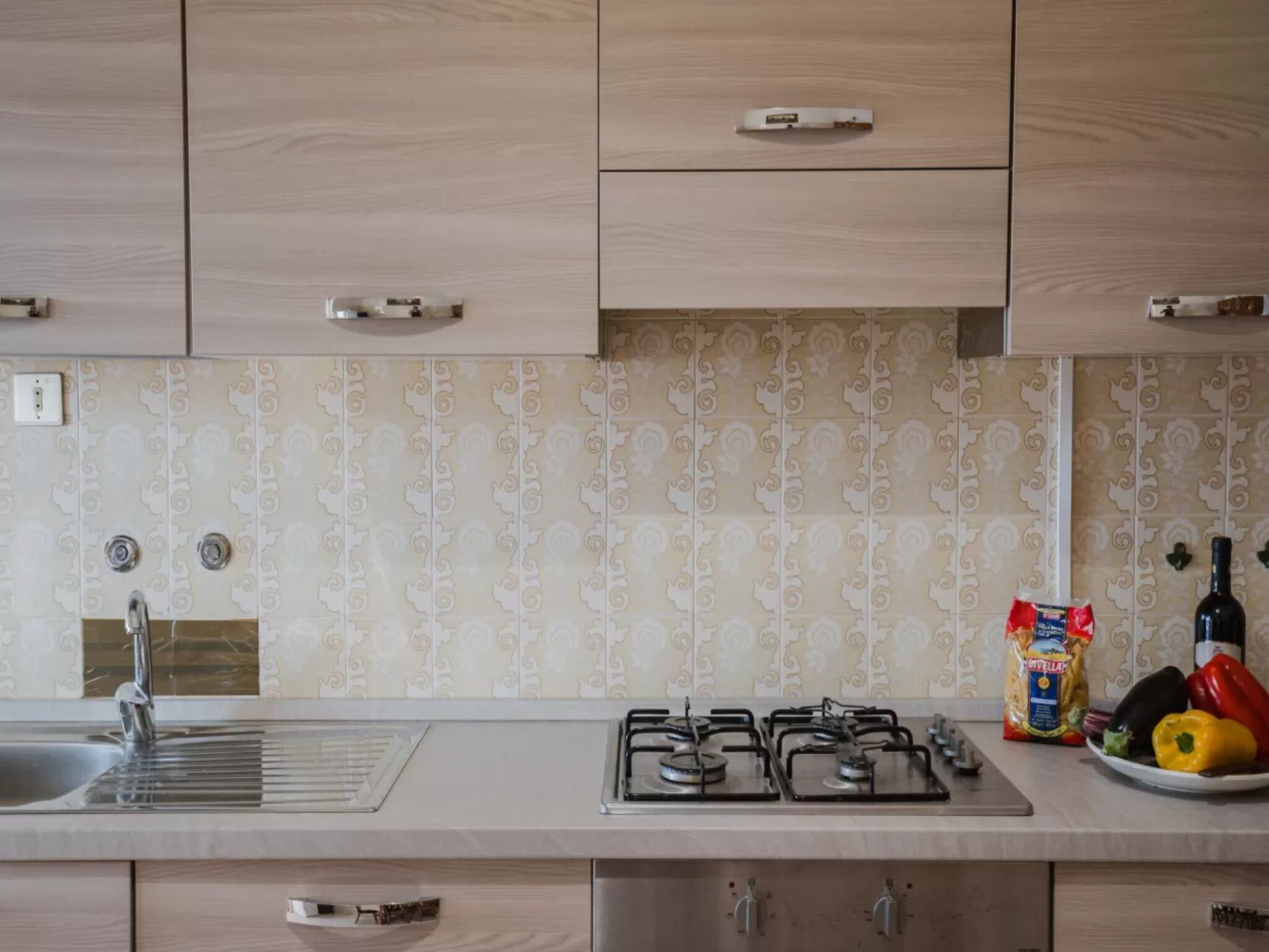 A kitchen with a gas stove, a sink, and a decorative backsplash.