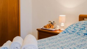 A hotel room with a bed, a nightstand with a lamp, and a plate of food.