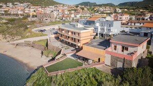 A coastal residential area with modern buildings, a beach, and a hilly backdrop.
