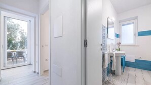 A modern bathroom with a sink, mirror, and window. - Spacious Retreat in the Heart of Sardinia (Dorgali)