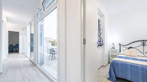 A bedroom with a large sliding glass door leading to an outdoor area, a bed with a blue bedspread, and a small bedside table. - Spacious Retreat in the Heart of Sardinia (Dorgali)