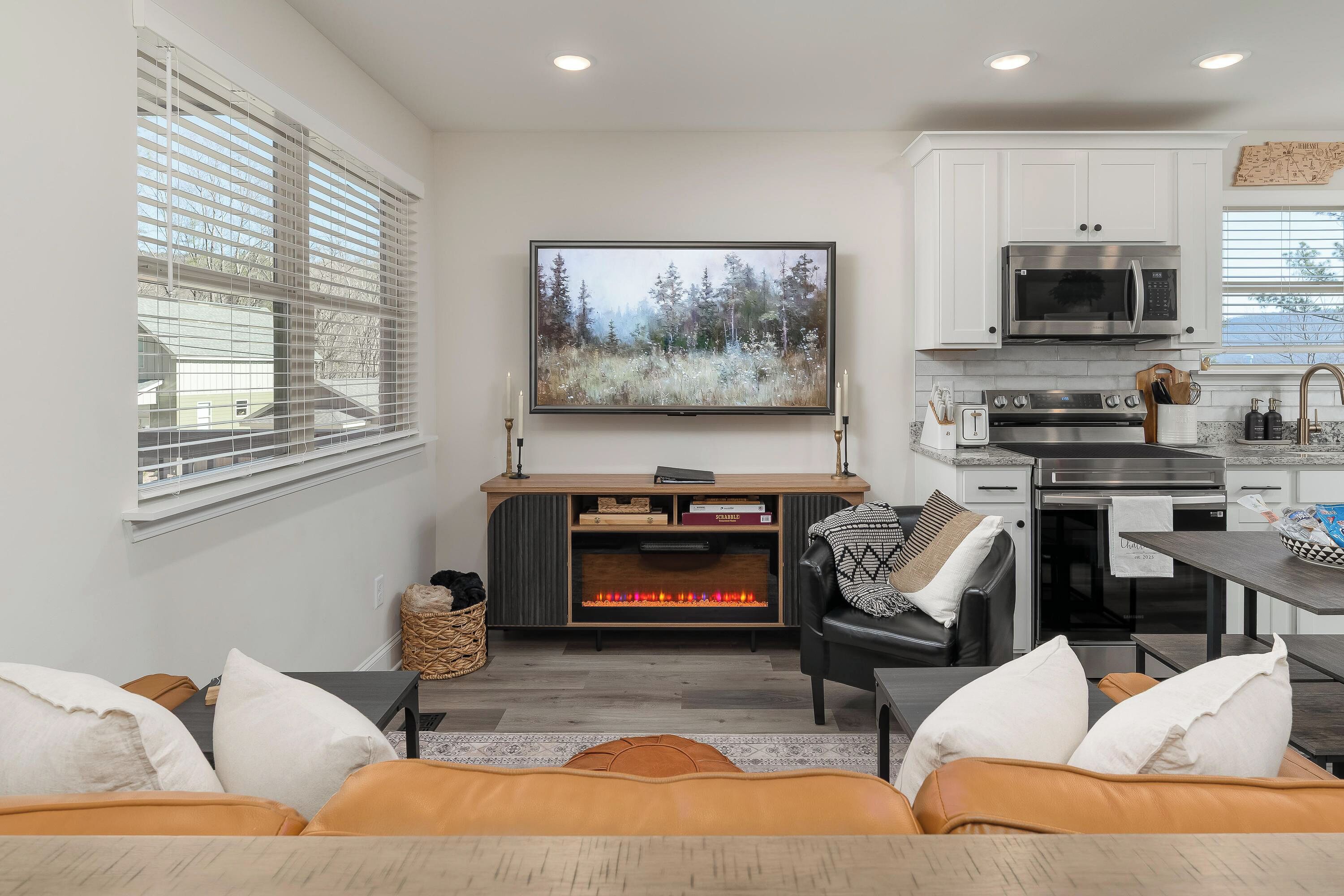 A modern living room with a fireplace, a sofa, and a kitchen area with a microwave and stove.