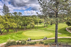 A golf course with a well-maintained green, sand bunkers, and a clear sky.