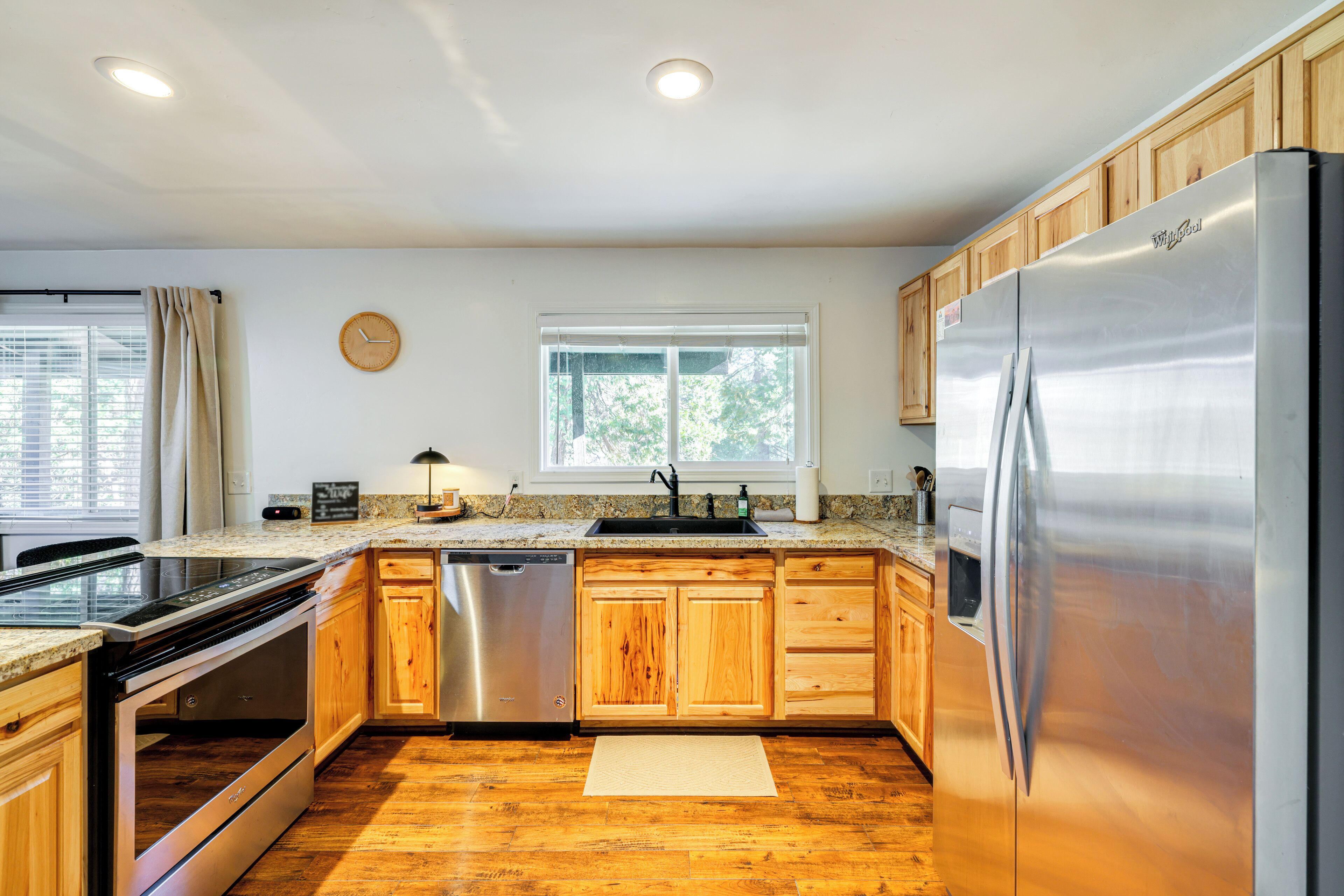Una cocina moderna con armarios de madera, electrodomésticos de acero inoxidable, lavavajillas y refrigerador.