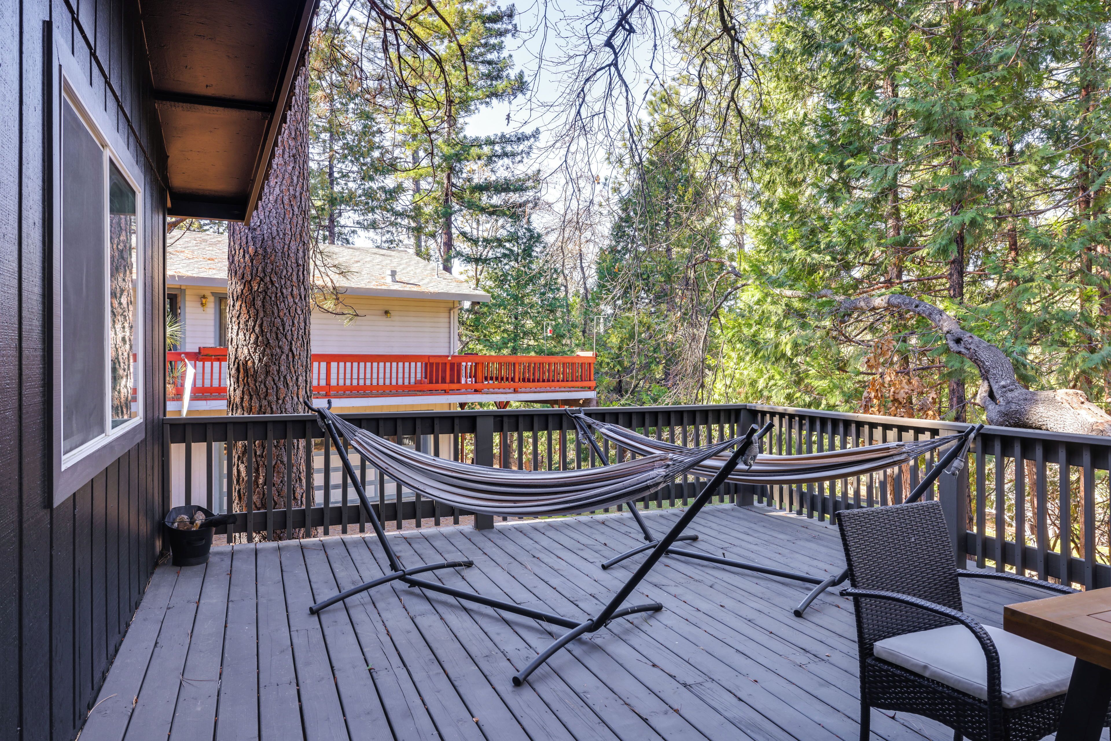 A wooden deck with a hammock, a wicker chair, and a table.