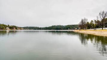 A calm lake with a forested shoreline and a small building in the distance.