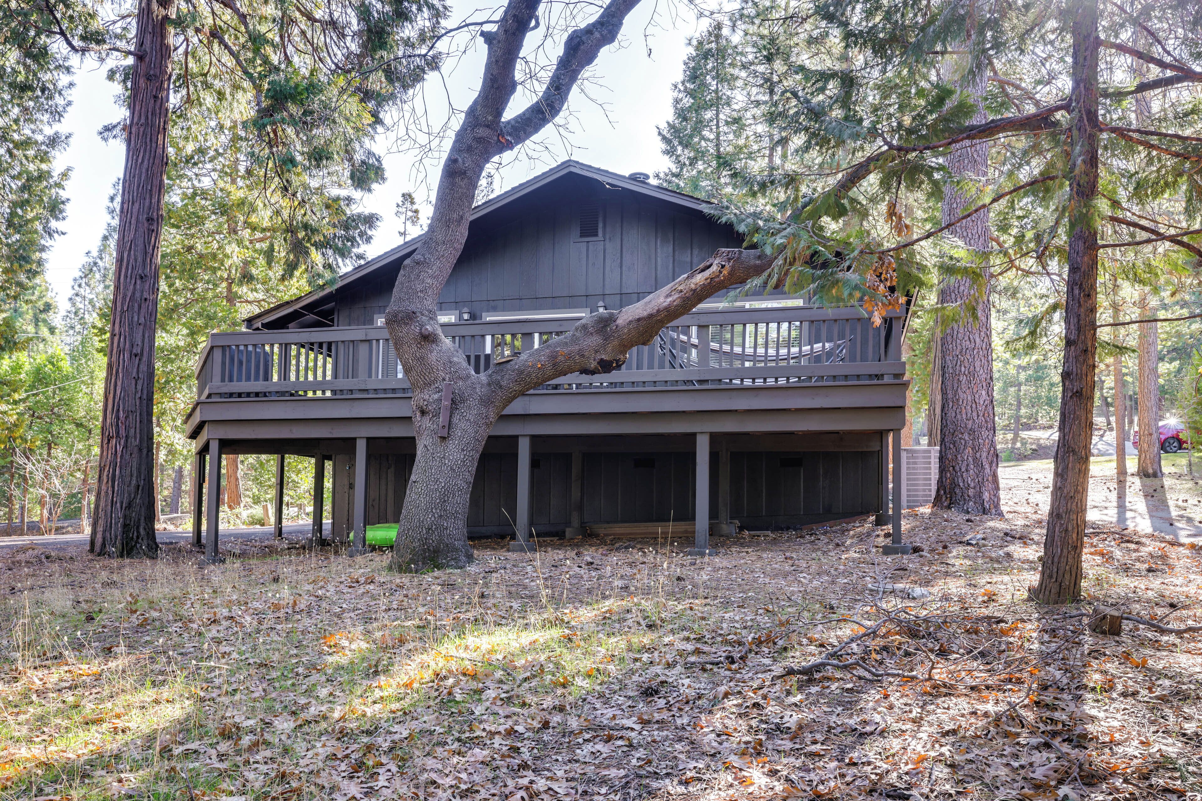 A two-story wooden cabin with a balcony, surrounded by trees.