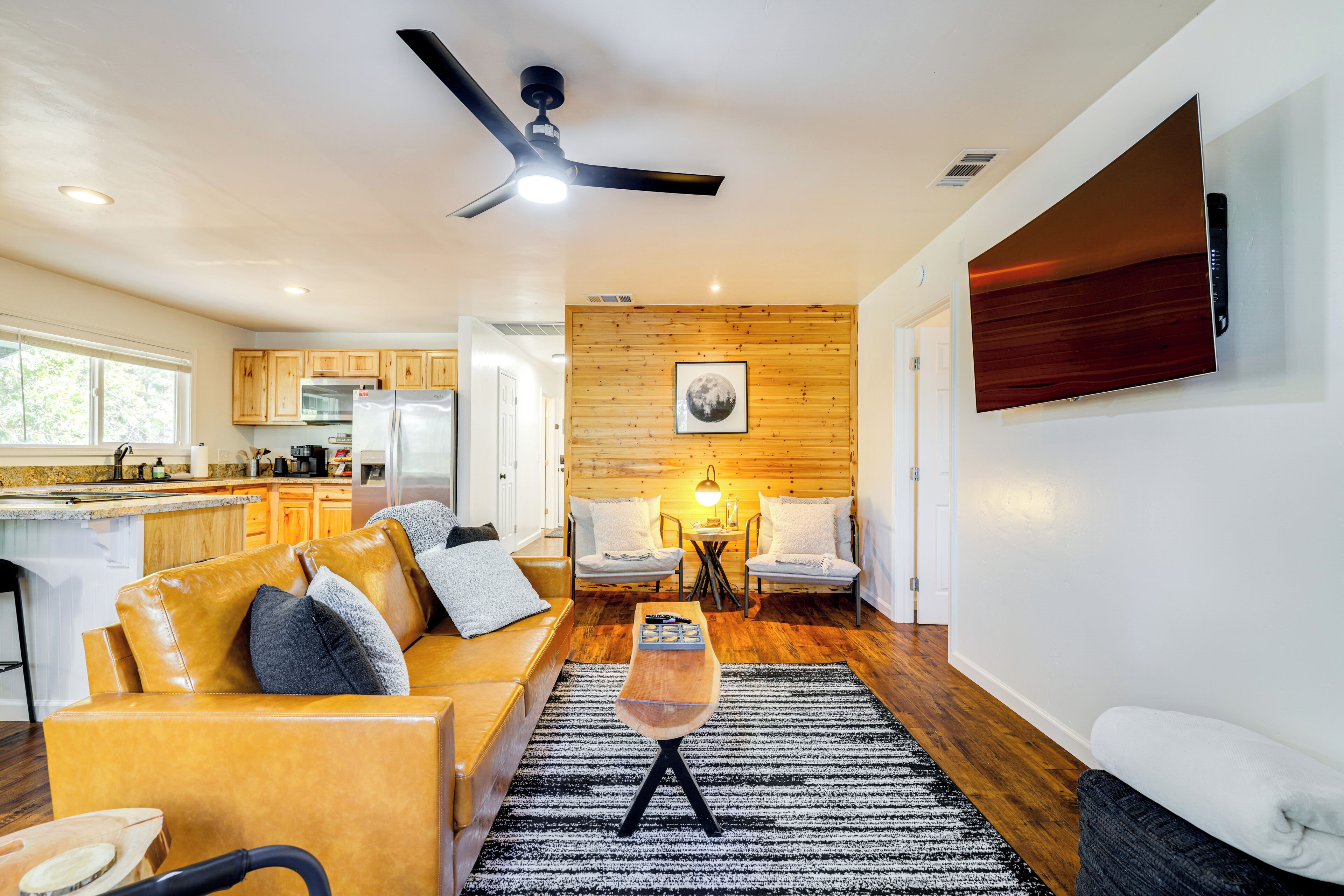 A modern living room with a sofa, chairs, a coffee table, and a TV mounted on the wall.