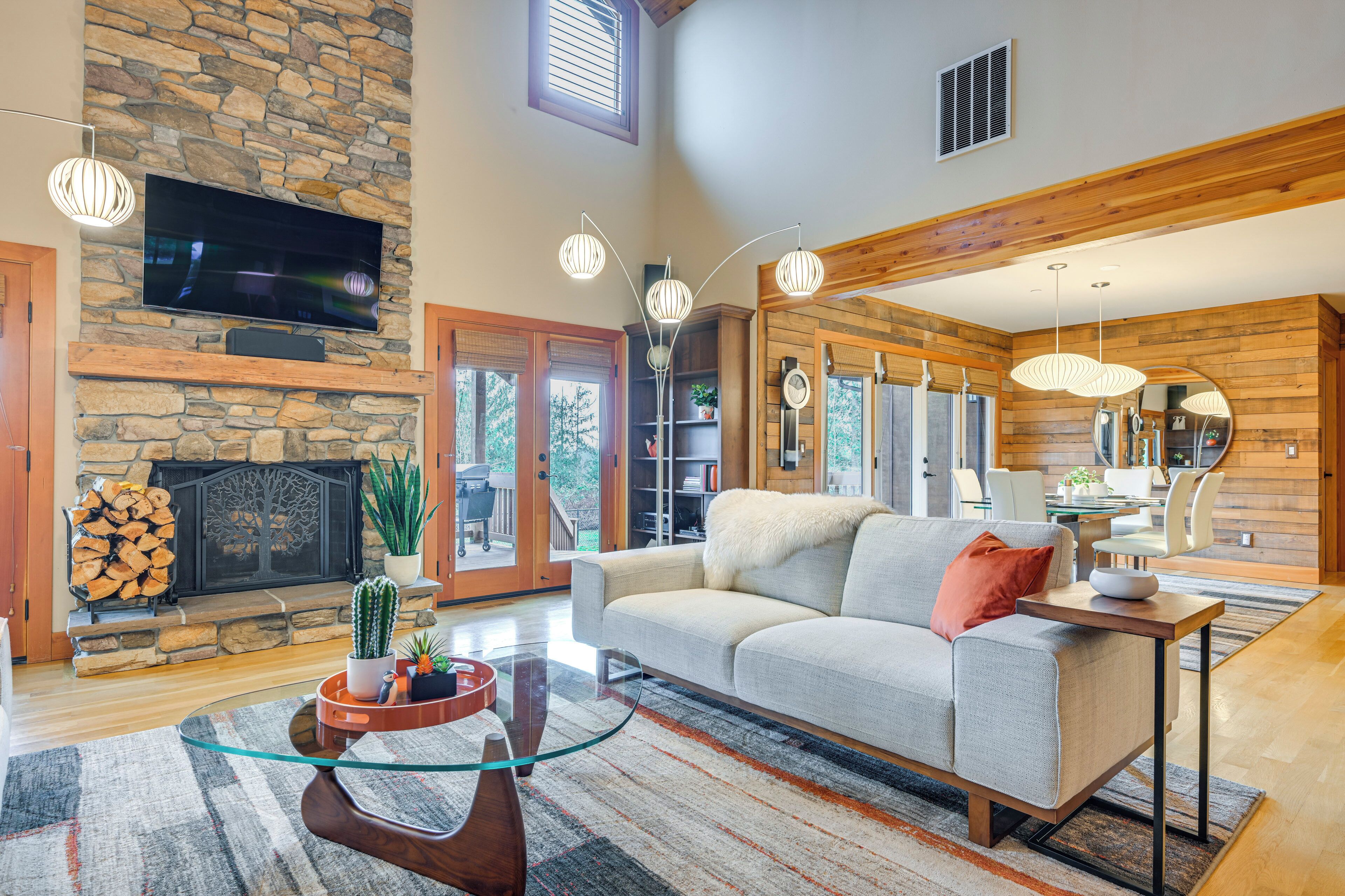 A spacious living room with a stone fireplace, a flat-screen TV, and a cozy seating area with a sofa and a coffee table.