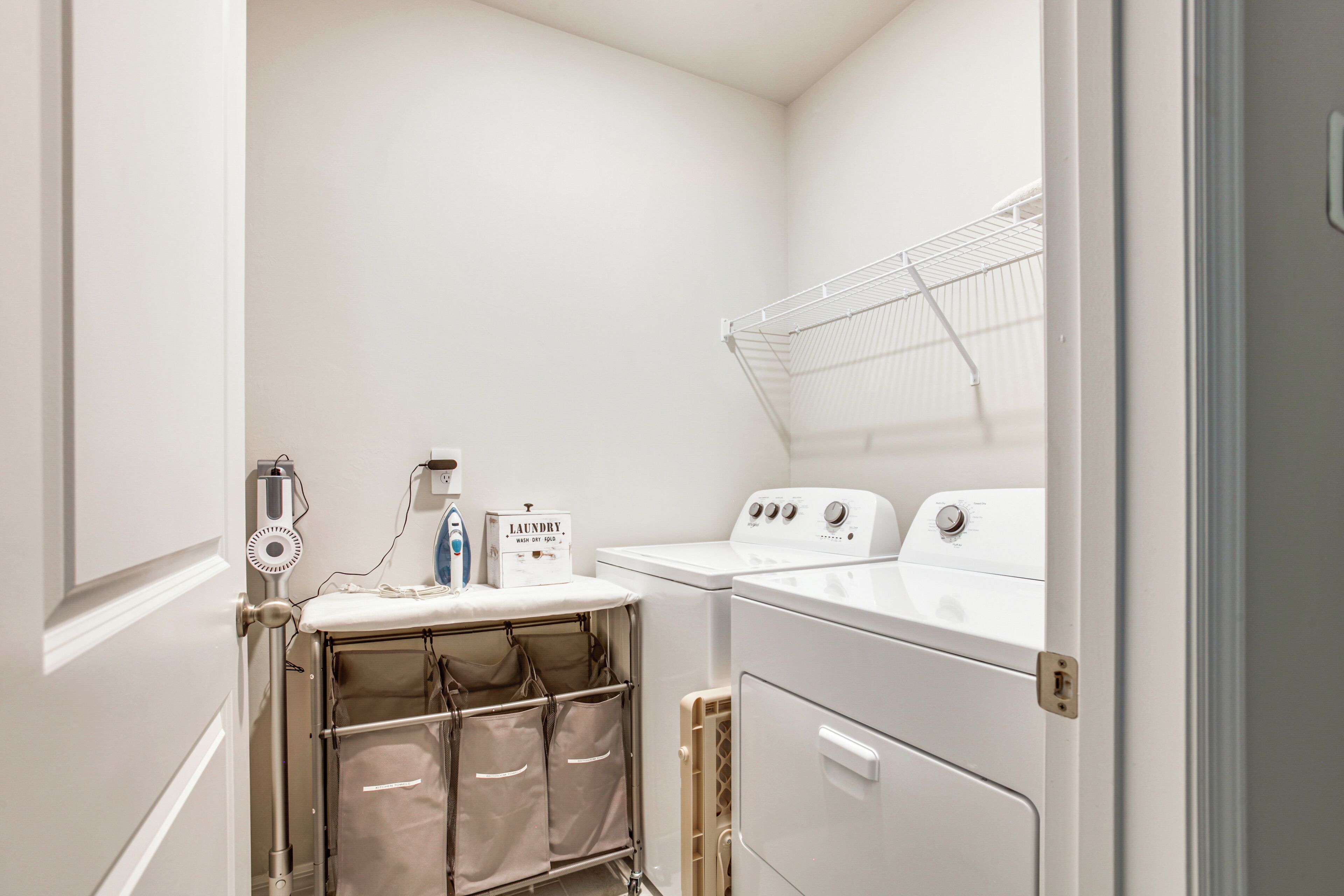 A laundry room with a washing machine, dryer, and a drying rack.