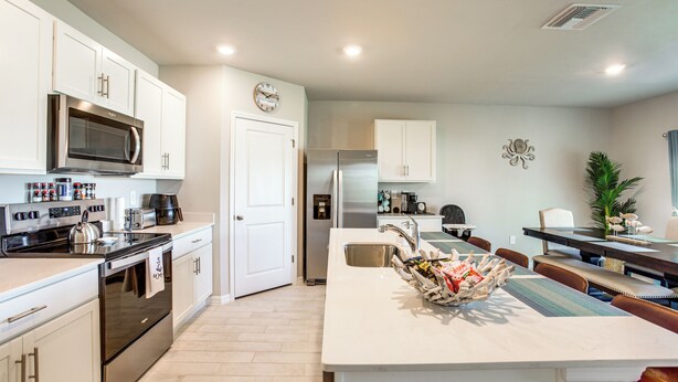 A modern kitchen with stainless steel appliances, white cabinetry, and a central island with a sink. - Coastal Gem w/ Patio & Grill in Punta Gorda! (Punta Gorda)