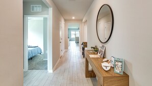 A hallway with a wooden bench, a mirror, and a door leading to a bedroom. - Coastal Gem w/ Patio & Grill in Punta Gorda! (Punta Gorda)