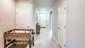 A hallway with a foosball table, white doors, and a tiled floor. - Coastal Gem w/ Patio & Grill in Punta Gorda! (Punta Gorda)
