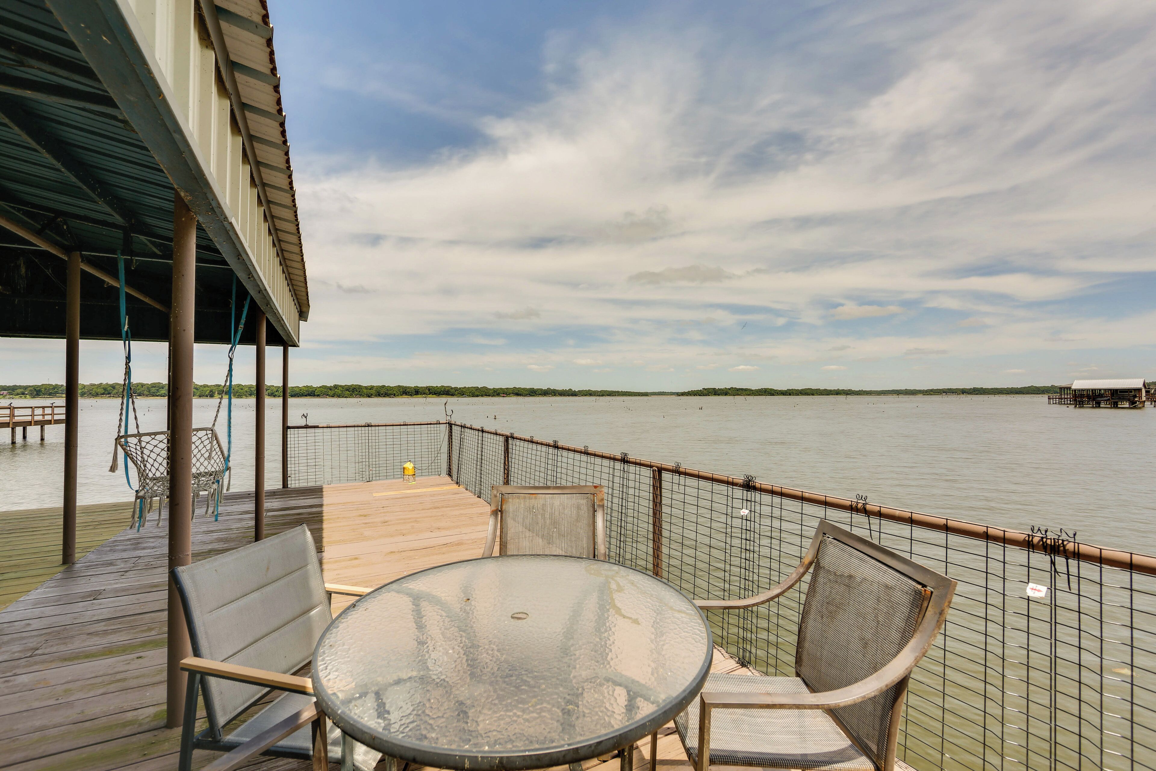Una terrazza con tavolo e sedie in vetro, con vista su un corpo d'acqua.