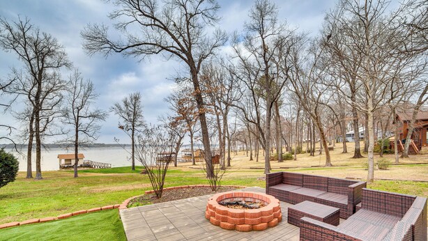 Une terrasse dotée d’un foyer extérieur, de mobilier de jardin et offrant une vue sur un lac.