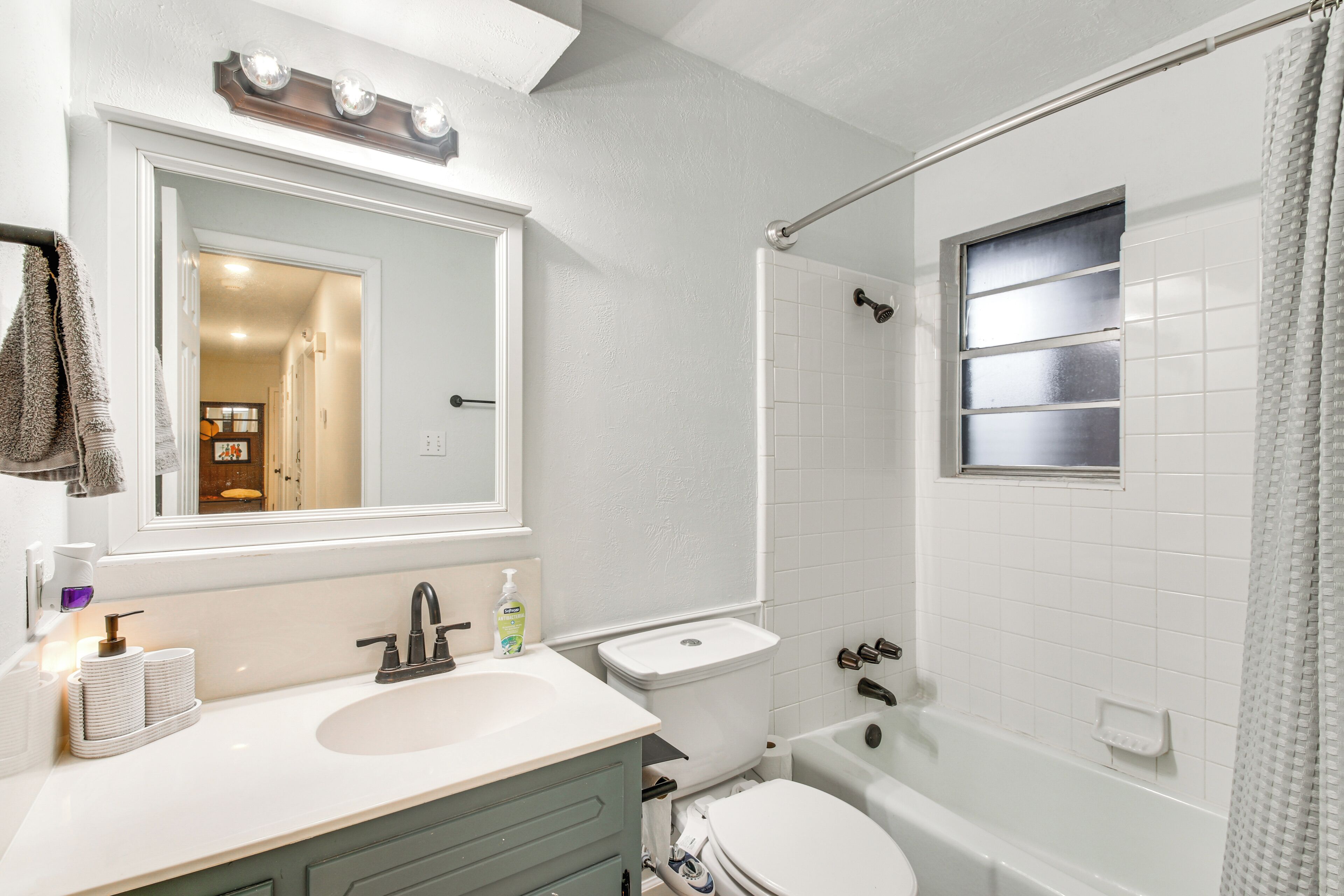 A bathroom with a sink, mirror, toilet, and bathtub.