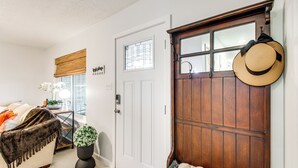 A room with a white door, a wooden door with a mirror and hat, a bed with a blanket, a potted plant, and a window with blinds. - 5 Mi to Museum of the Great Plains: Home w/ Patio (Lawton)