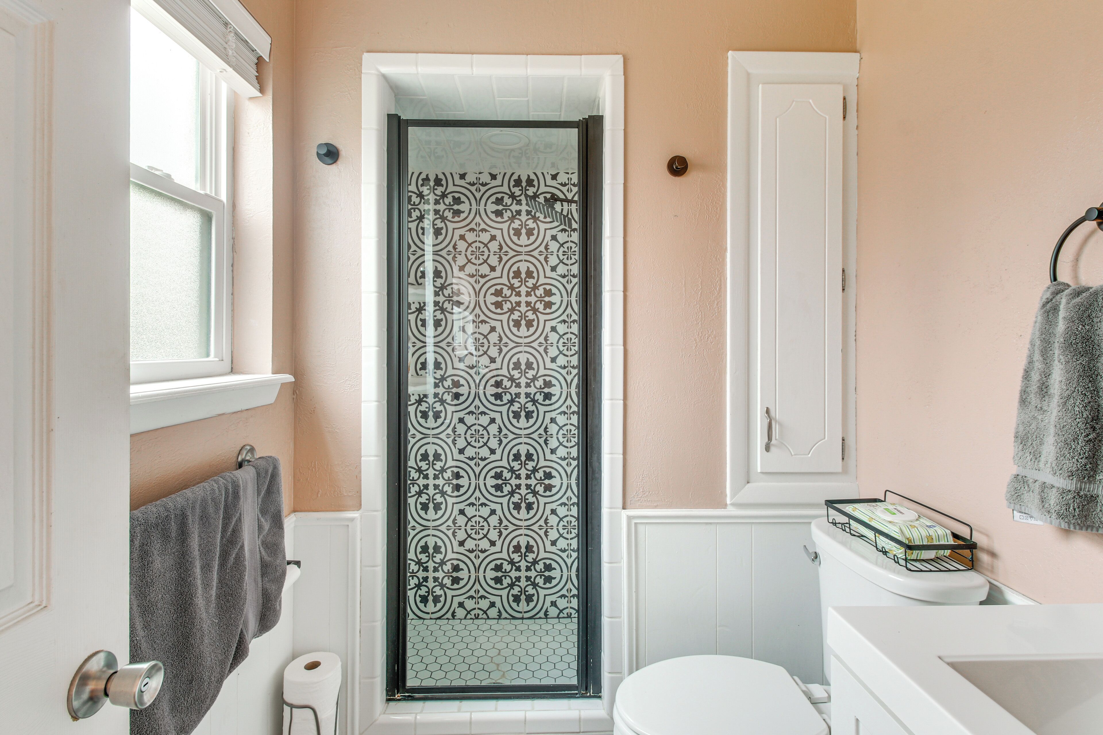Un bagno con una porta doccia decorata, un water, un lavandino e un portasciugamani.
