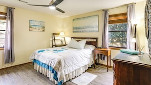 A bedroom with a bed, a nightstand, a desk, a ceiling fan, and a window with curtains. - Cozy Home w/ Fenced Backyard in Sunset Beach! (Sunset Beach)