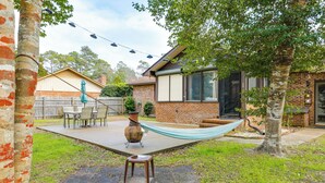 A backyard with a hammock, a patio table, and a brick house. - Cozy Home w/ Fenced Backyard in Sunset Beach! (Sunset Beach)