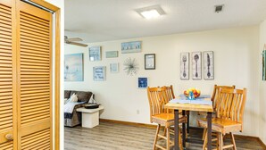 A dining area with a wooden table and chairs, a white wall with framed artwork, and a wooden floor. - Cozy Home w/ Fenced Backyard in Sunset Beach! (Sunset Beach)