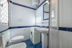 A bathroom with a toilet, washing machine, and sink.