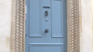 Una porta blava amb detalls ornamentals tallats i un marc decoratiu.