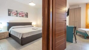 A bedroom with a bed, bedside table, lamp, and a painting on the wall. - Seaside Comfort in the Heart of Alghero (Alghero)