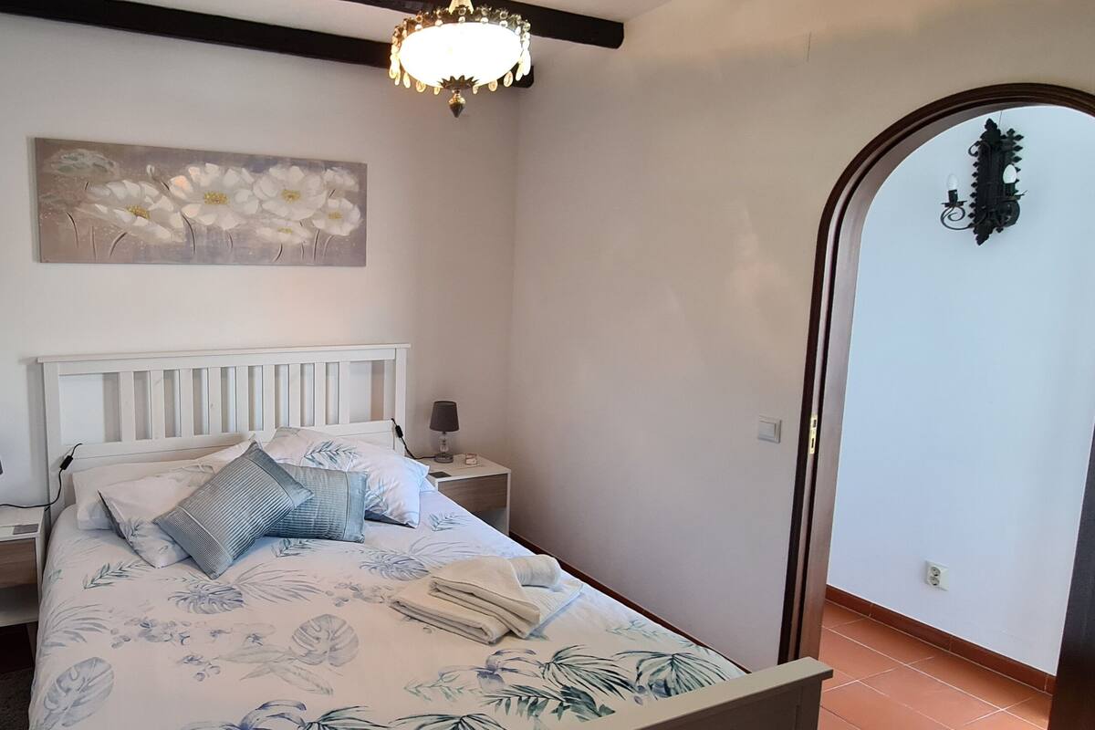 Une chambre à coucher avec un lit, des tables de chevet, une lampe, un tableau et une porte.
