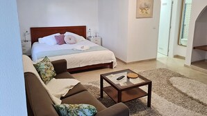 Een slaapkamer met een bed, nachtkastje, bijzettafeltje en een bank.
