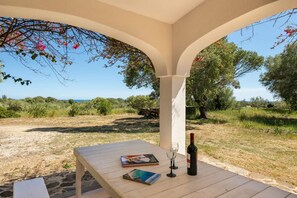 A covered outdoor seating area with a table, two wine glasses, and a bottle of wine. - Lovely Cottage With Garden Near Orosei (Orosei)