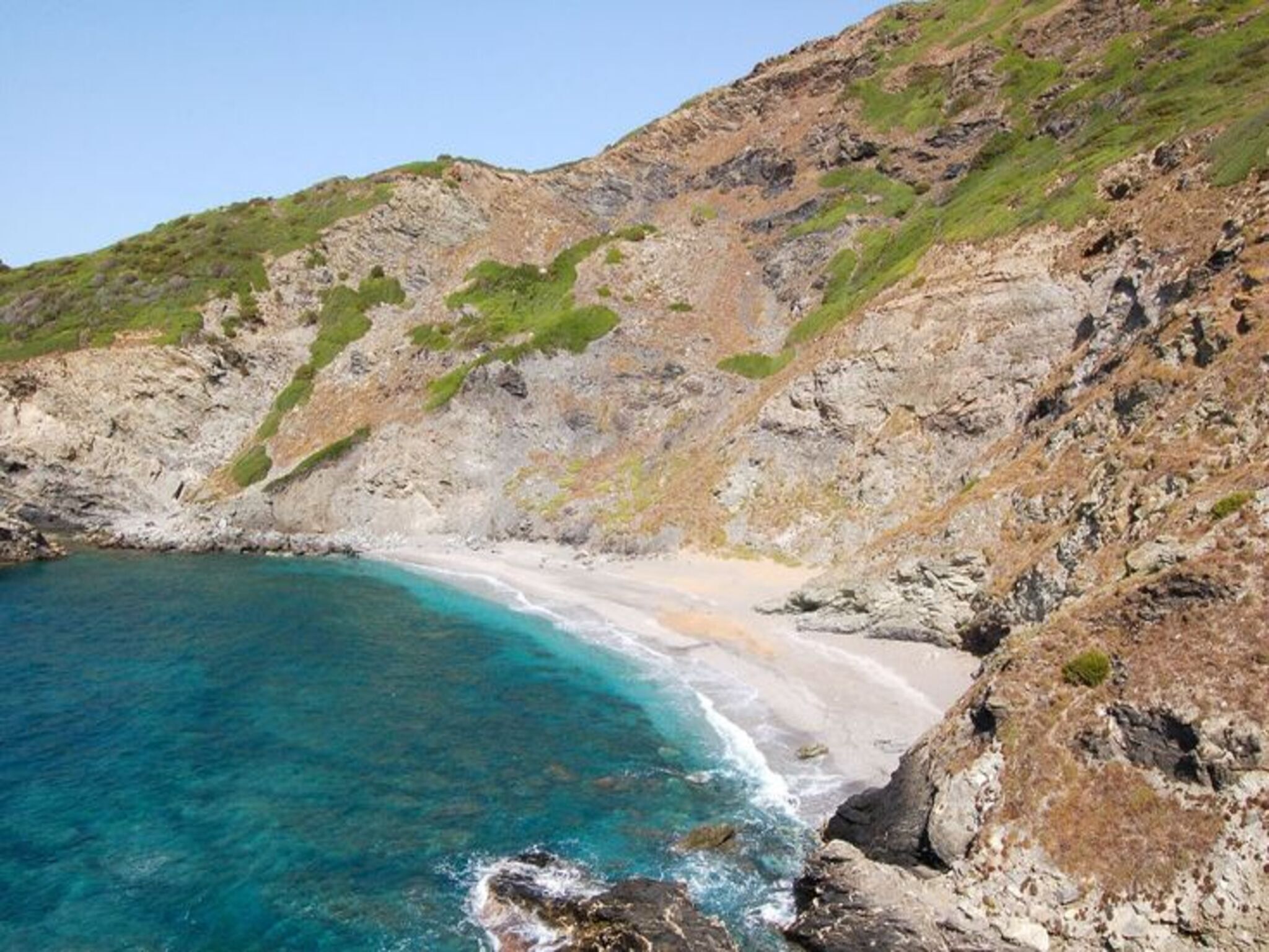 A coastal landscape with a rocky beach and clear turquoise waters.