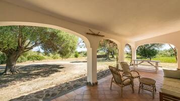 Relax in a serene outdoor space with a sheltered patio area, wicker chairs, and a small table.