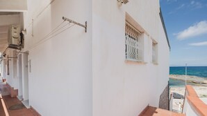 A white building with a tiled balcony overlooking a beach. - Breathtaking Seaview Flat in Sardinia (Porto Torres)