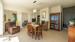 Amplia sala de estar con comedor, chimenea y un mueble grande con puertas de vidrio.