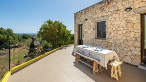 Un edificio de piedra con un balcón, una mesa dispuesta para comer y vistas al paisaje.