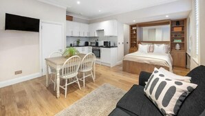 Een compact appartement met een kitchenette, een eethoek en een slaapkamer.