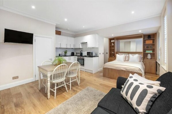 A compact apartment with a kitchenette, a dining area, and a bedroom. - Chelsea Edition Studio Apt (London)