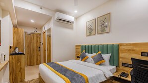 Habitación de hotel con cama de madera, escritorio con teléfono y cabecero tapizado en verde.