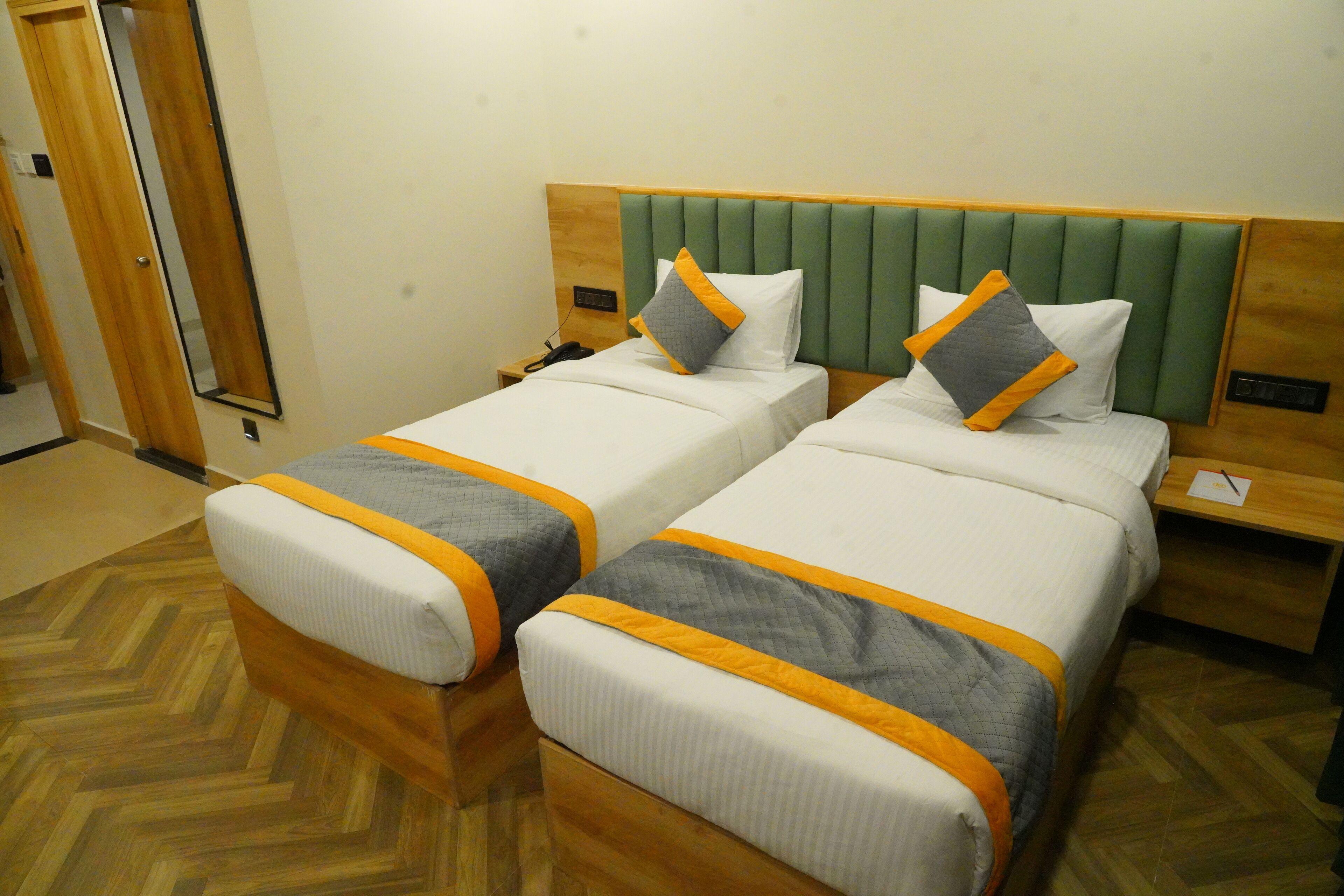 Habitación de hotel con dos camas, cada una con cabecero de madera y mesitas de noche a juego.