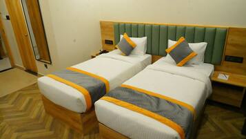 Habitación de hotel con dos camas, cada una con cabecero de madera y mesitas de noche a juego.