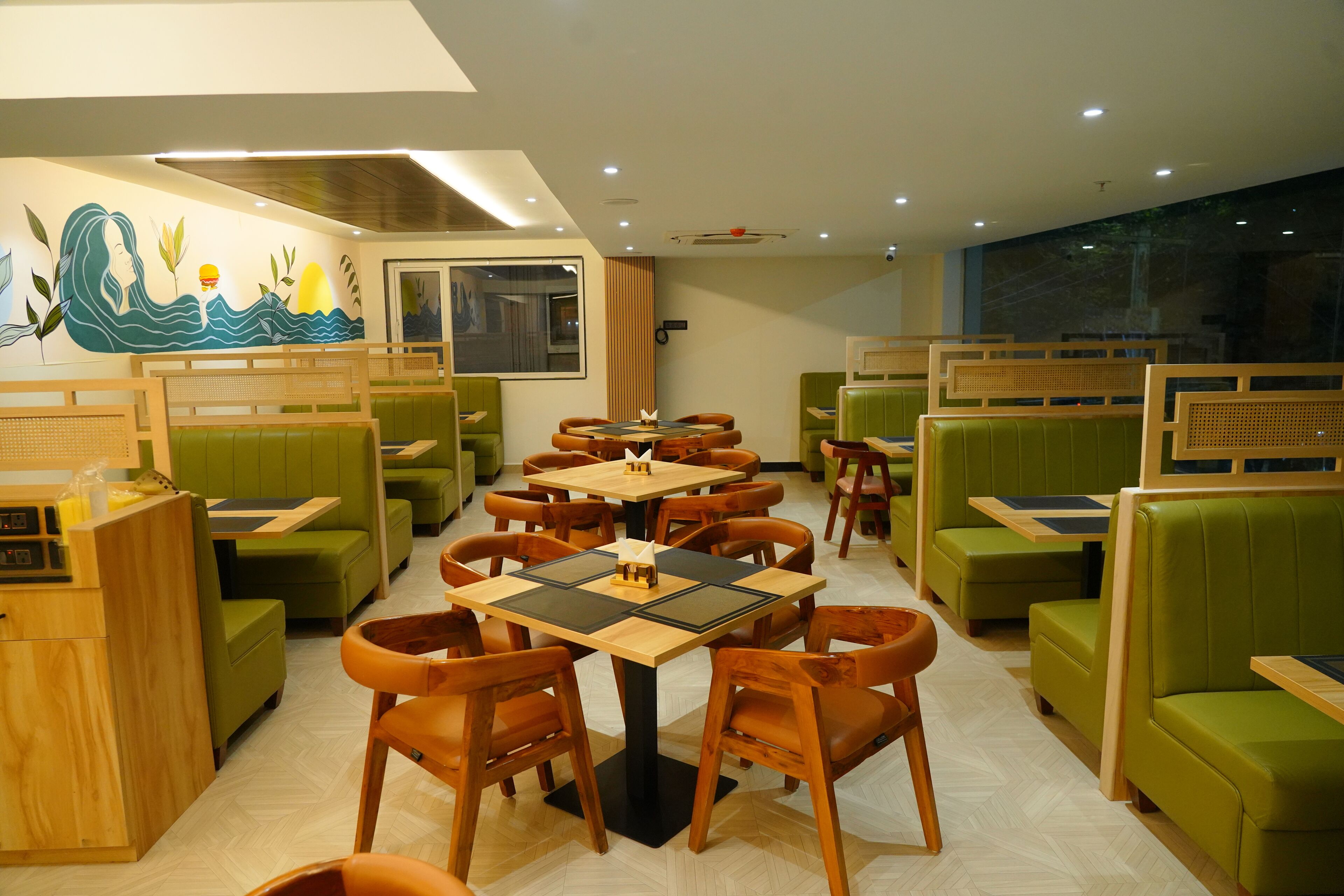 A restaurant with green booths and wooden tables.