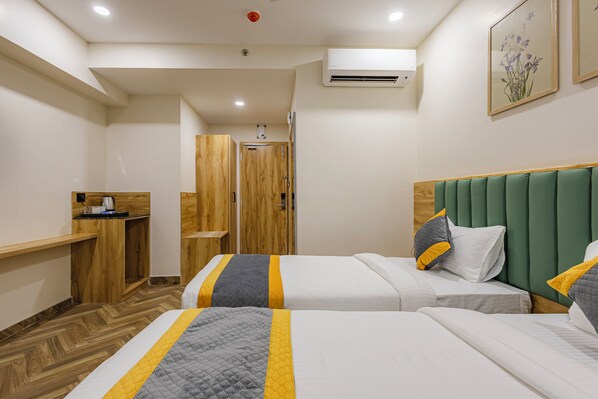 A hotel room with two beds, a wooden desk, and a shower area. - Lemonridge Hotels KPHB (Hyderabad)